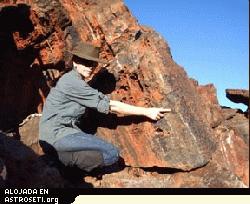 La imagen muestra a Abigail Allwood de la Universidad Macquarie señalando el arrecife fósil que descubrió en Pilbara
