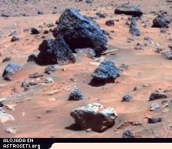 Pinche <a href="http://www.planetary.org/image/Spirit_AllanHills_meteorite_false-color-A865R1_063006_br2.jpg">aquí</a> para ampliar la imagen
<strong>Allan Hills-en Marte</strong>
La roca de tono gris claro en el centro del primer plano de esta imagen es sospechoso de ser un meteorito de hierro. Spirit tomó esta imagen con la PanCam durante el Sol 809 (12 de Abril, 2006), no mucho después de llegar a su refugio de invierno, Low Ridge. Esta roca, llamada Allan Hills, y una roca similar llamada Zhong Shan, justo fuera del campo de visión hacia la izquierda, tiene una textura más suave y un tono más claro que otras rocas en la zona. La textura y el brillo de este par recordaron a algunos de los miembros del equipo científico del rover a una roca llamada Heat Shield Rock, observada por Opportunity en la zona de Meridiani de Marte hace más de un año. El examen de la composición de esa roca confirmó que se trataba de un meteorito de hierro. Esta imagen es una versión a color falso para enfatizar las diferencias entre los materiales de roca y de suelo.
Crédito: NASA/JPL-Caltech/Cornell