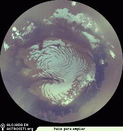 Esta imagen MARCI de la MRO es la composicin de un mosaico del casquete polar norte.  Las imgenes fueron tomadas a media noche, a las 6 de la maana y a las seis de la tarde (hora de Marte), durante el verano, cuando el Sol ilumina la regin de forma ininterrumpida.  La imagen muestra la mayor parte del casquete perenne de agua y hielo (zona blanca), asentada sobre los materiales estratificados del polo norte (zona marrn adyacente al hielo) y las oscuras dunas circumpolares.
Crdito imagen: NASA/JPL/MSSS