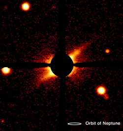 La imagen en luz visible del disco circunestelar que rodea a la joven estrella AU Mic fue descubierta mediante el telescopio de 2,2 metros de la Universidad de Hawai. El disco se ve de canto, revelado por la luz estelar dispersa por los pequeños granos de polvo. El largo total es de aproximadamente 210 Unidades Astronómicas. Una máscara opaca y sus filamentos entrecruzados de sostén bloquean la brillante luz de la estrella, permitiendo la detección del disco tenue. El análisis de la radiación de AU Mic muestra que el disco interior no contiene material, lo que supone una prueba indirecta de planetas recién formados en la región interna. Crédito: Hawaii