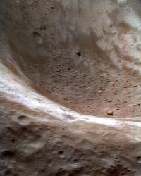 Imagen de rocas dentro de un cráter en el asteroide Eros, tomadas antes del impacto con la astronave NEAR. Numerosas señales en el asteroide muestran grandes piedras marrones visibles dentro de otras menos expuestas (blancas) en el borde del cráter. Se ha dado un falso color a la imagen para recalcar lo anterior. Fuente de la imagen: NASA/Eros