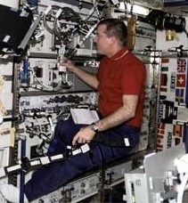 El astronauta Jim Voss de la expedición 2 de la I.S.S. atendiendo los módulos de crecimiento de las plantas en la Unidad de Laboratorio del módulo.