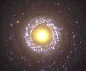 Aunque puede recordarnos al huevo frito de nuestro desayuno, en realidad es mucho más grande. De hecho, rodeada por brazos espirales teñidos de azul, débilmente visibles, formadores de estrellas, la amarilla yema central de esta galaxia en visión frontal NGC 7742, tiene una anchura de unos 3,000 años luz. Como NGC 5548, esta galaxia es de tipo Seyfert, una clase de galaxia espiral activa con un centro o núcleo muy brillante en longitudes de onda visibles. Se piensa que galaxias como la NGC 7742 y 5548 pueden albergar agujeros negros masivos en su corazón.