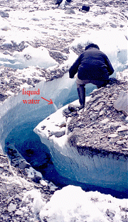 Tomando muestras de hielo desde una grieta en la lengua del glaciar Matanuska de Alaska. Puede verse musgo anaranjado creciendo en restos de roca quebrada sobre salientes de hielo. [<A HREF= http://science.nasa.gov/headlines/images/marssalt/mat_moulin_moss.jpg target=_blank>imagen amplia</A>] (Fotos cortesa de Richard B. Hoover)