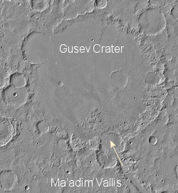 Una imagen del Crter Gusev de la Mars Globar Surveyor. La flecha indica la direccin de la posible agua fluyendo hasta el crter. <A HREF= http://marsoweb.nas.nasa.gov/landingsites/mer2003/topsites/final/ target=_blank>[ms]</A>
