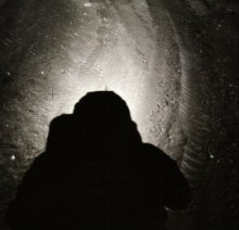 Un plateado resplandor rodea la sombra del casco de un astronauta del Apolo.  Del libro FULL MOON por <a href=http://www.michaellight.net/fullmoon/index.html target=_blank>Michael Light</a>. Alfred A. Knopf 1999