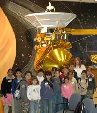 Los estudiantes y su maestra Kathy Cooper, enfrente de un modelo a mediana escala de la sonda Cassini en JPL.