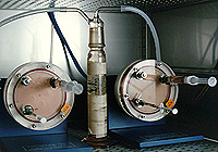Dos matraces de gran tamaño radial girando a unas 12 rpm para mantener las formaciones de tejido mamario suspendidas dentro del medio de cultivo. Las jeringas permiten a los científicos tomar muestras para análisis durante las secuencias de crecimiento. El tubo central es una fuente de agua que deshumidifica el aire para prevenir la evaporación del medio y así la aparición de burbujas perjudiciales en el biorreactor.